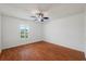 Bright bedroom featuring hardwood floors, a ceiling fan, and a window overlooking the yard at 13420 Copper Head Dr, Riverview, FL 33569