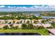 An aerial view showcasing a home with a well-maintained tile roof, landscaping, and lake access in a residential neighborhood at 16261 Amethyst Key Dr, Wimauma, FL 33598