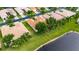 An aerial view showcasing a home with a well-maintained tile roof, landscaping, and lake access in a residential neighborhood at 16261 Amethyst Key Dr, Wimauma, FL 33598