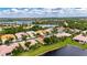 An aerial view showcasing a home with a well-maintained tile roof, landscaping, and lake access in a residential neighborhood at 16261 Amethyst Key Dr, Wimauma, FL 33598