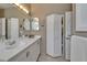 Neutral bathroom with an extended vanity, updated mirrors and lighting, and closet access at 16261 Amethyst Key Dr, Wimauma, FL 33598