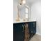 Stylish bathroom with double vanity, unique mirror, and bold navy blue cabinets at 1698 Eden Ct, Clearwater, FL 33756