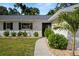 Inviting front entrance with a walkway, lush green shrubs, and a freshly painted white exterior with black shutters at 1698 Eden Ct, Clearwater, FL 33756