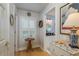 Hallway with hardwood floors, table and decor leading to bathroom with white vanity and decorative mirror at 18106 Woodcreek Pl, Lutz, FL 33548