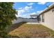 View of backyard featuring white fence, covered porch, and large shade tree at 18314 Waydale Loop, Hudson, FL 34667