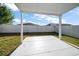 Backyard featuring a covered patio area with a concrete slab, a white fence and grass at 18314 Waydale Loop, Hudson, FL 34667