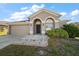 Well-maintained home with a two-car garage, arched entryway, and a tidy, green lawn at 18314 Waydale Loop, Hudson, FL 34667