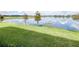 Backyard view of a green lush lawn with an expansive lake in the background at 19195 Blue Pond Dr, Lutz, FL 33558