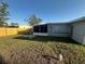 Fenced-in backyard featuring the home's light gray exterior, screened patio, and lush lawn at 21042 Gladis Ave, Port Charlotte, FL 33952