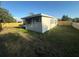 The fenced backyard features lush green grass, home's light gray siding, and windowed exterior walls at 21042 Gladis Ave, Port Charlotte, FL 33952