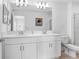 Bathroom with double sinks, white cabinets, and a large mirror, providing a clean aesthetic at 2265 Alee Ln, Wesley Chapel, FL 33543