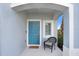 Inviting front porch with blue door, chair, and neutral finishes create a cozy welcome to the home at 2265 Alee Ln, Wesley Chapel, FL 33543
