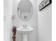 Neat half bathroom with a pedestal sink, decorative mirror, and neutral walls at 2265 Alee Ln, Wesley Chapel, FL 33543