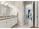 Bathroom with double sinks, granite countertop, white cabinets and an open doorway to the bedroom at 2835 Hilliard Dr, Wesley Chapel, FL 33543