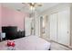 Bedroom with pink accent wall, ceiling fan, closet, an open doorway to the bathroom and wood-style floors at 2835 Hilliard Dr, Wesley Chapel, FL 33543