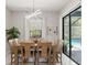 Bright dining room featuring modern light fixture and views of a screened-in pool and patio at 2835 Hilliard Dr, Wesley Chapel, FL 33543