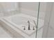 A close up of a bright white soaking tub with tile surround and decorative, modern fixtures at 2969 Talon Dr, Clearwater, FL 33761