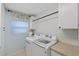 Bright laundry room featuring a front load washer and dryer, overhead cabinets, and a window with a floral valance at 2969 Talon Dr, Clearwater, FL 33761
