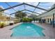 Enclosed in-ground pool with a screened lanai, comfortable lounge furniture, a built-in grill, and lush landscaping at 2969 Talon Dr, Clearwater, FL 33761