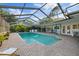 Stunning screened-in pool area with brick pavers, lush landscaping, and a relaxing lounge chair under the blue sky at 2969 Talon Dr, Clearwater, FL 33761