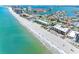 Expansive aerial view of beach front condominiums along a pristine beach, showcasing the clear, turquoise waters at 3210 Gulf Blvd # 108, Belleair Beach, FL 33786