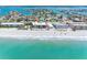 Stunning aerial view of the beach front condos along a pristine beach with turquoise waters and nearby residential homes at 3210 Gulf Blvd # 108, Belleair Beach, FL 33786