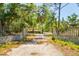 Long driveway leading to a charming home, framed by a gated entrance and mature trees at 3226 Palmetto Rd, Wimauma, FL 33598