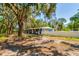 Exterior view of a blue single-story home with white trim surrounded by trees and a white fence at 3226 Palmetto Rd, Wimauma, FL 33598