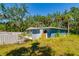 The blue exterior of the home is surrounded by overgrown foliage and debris at 3226 Palmetto Rd, Wimauma, FL 33598