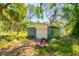 View of the property's garage surrounded by lush trees, vegetation, and assorted outdoor debris at 3226 Palmetto Rd, Wimauma, FL 33598