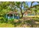 Property view shows the home and a blue gazebo surrounded by overgrown landscape at 3226 Palmetto Rd, Wimauma, FL 33598