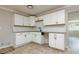 Bright, tiled kitchen with modern white cabinetry, black hardware, and views into the adjacent living area at 3226 Palmetto Rd, Wimauma, FL 33598