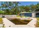 Exterior view of a murky in-ground pool surrounded by a cracked concrete deck, adjacent to a blue house at 3226 Palmetto Rd, Wimauma, FL 33598
