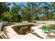 Exterior view of a murky in-ground pool surrounded by a cracked concrete deck and overgrown landscaping at 3226 Palmetto Rd, Wimauma, FL 33598