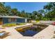 Exterior view of a murky in-ground pool surrounded by a cracked concrete deck near a blue house at 3226 Palmetto Rd, Wimauma, FL 33598