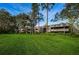 Exterior view showcasing lush lawn and mature trees surrounding well-maintained condo buildings at 36750 Us 19 N # 5-111, Palm Harbor, FL 34684