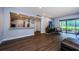 Open living room featuring wood floors, partial kitchen view, TV, and sliding glass doors to the outdoors at 36750 Us 19 N # 5-111, Palm Harbor, FL 34684