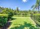 The backyard has well-maintained lawn with a lake view, framed by mature trees and landscaping at 4848 Quill Ct, Palm Harbor, FL 34685