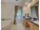 Bright bathroom featuring a soaking tub and dual sink vanity with granite countertops at 4848 Quill Ct, Palm Harbor, FL 34685
