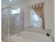 Bright bathroom featuring a soaking tub, glass shower, and window with elegant curtain at 4848 Quill Ct, Palm Harbor, FL 34685
