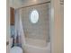 Bathroom featuring a bathtub, tile walls, and a decorative oval window at 4848 Quill Ct, Palm Harbor, FL 34685