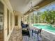 Covered patio with furniture and a view of the screened-in pool and lush landscaping at 4848 Quill Ct, Palm Harbor, FL 34685