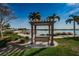 Outdoor park area with a bench under a pergola, palm trees and a view of the water at 5108 Brittany S Dr # 607, St Petersburg, FL 33715