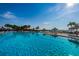 Large outdoor swimming pool with clear blue water surrounded by palm trees, beach umbrellas, and lounge chairs at 5108 Brittany S Dr # 607, St Petersburg, FL 33715