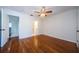 Bedroom with hardwood floors, ceiling fan, and open doorway to bathroom at 70 Ashley Ln, Oldsmar, FL 34677