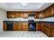 Traditional kitchen featuring wood cabinets, dark countertops, and black appliances at 70 Ashley Ln, Oldsmar, FL 34677