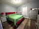 Cozy bedroom features wood floors, a red bed frame, and two matching silver nightstands at 8516 N Dixon Ave, Tampa, FL 33604
