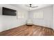 Bright bedroom featuring wood floors, ceiling fan, two windows with white shutters, and a TV at 8801 Gulf Blvd, St Petersburg, FL 33706