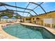 Screened-in pool area with chairs, umbrellas, an outdoor kitchen, and a pool with clear blue water at 8801 Gulf Blvd, St Petersburg, FL 33706