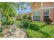 A beautiful walkway leads to a charming home with lush landscaping and a cozy bench seating area at 965 Westwinds Blvd, Tarpon Springs, FL 34689